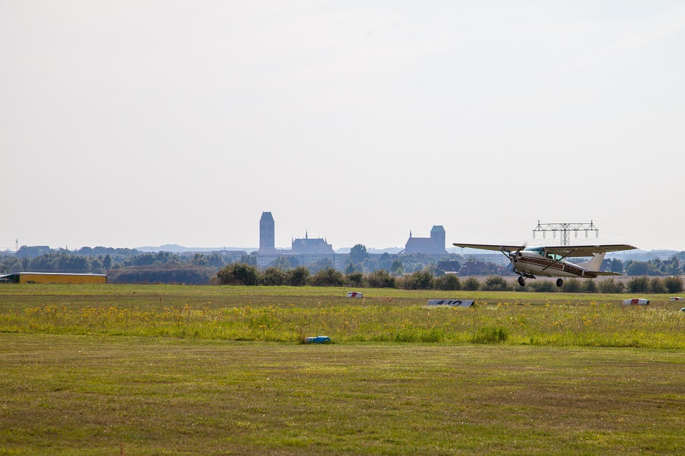 Flugzeug beim Start. Im Hintergrund die Silhouette von Wismar.